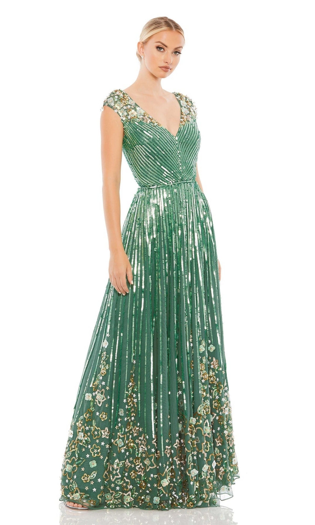 A woman stands against a white background wearing the Long Formal Dress 5223 by Mac Duggal, featuring sage green fabric, gold sequin floral accents, beaded cap sleeves, and a V-neckline.